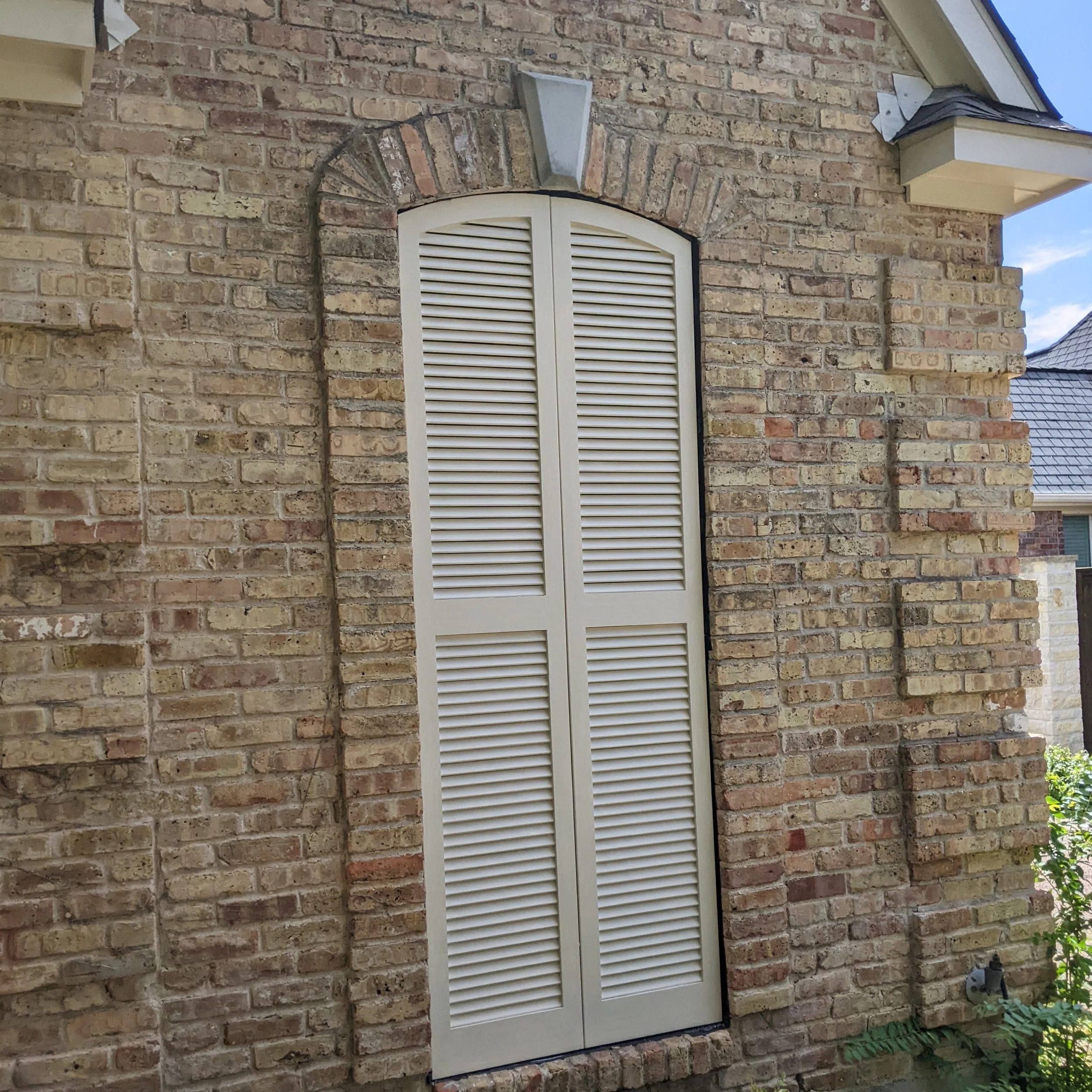 Arch-top cedar shutter built into brick